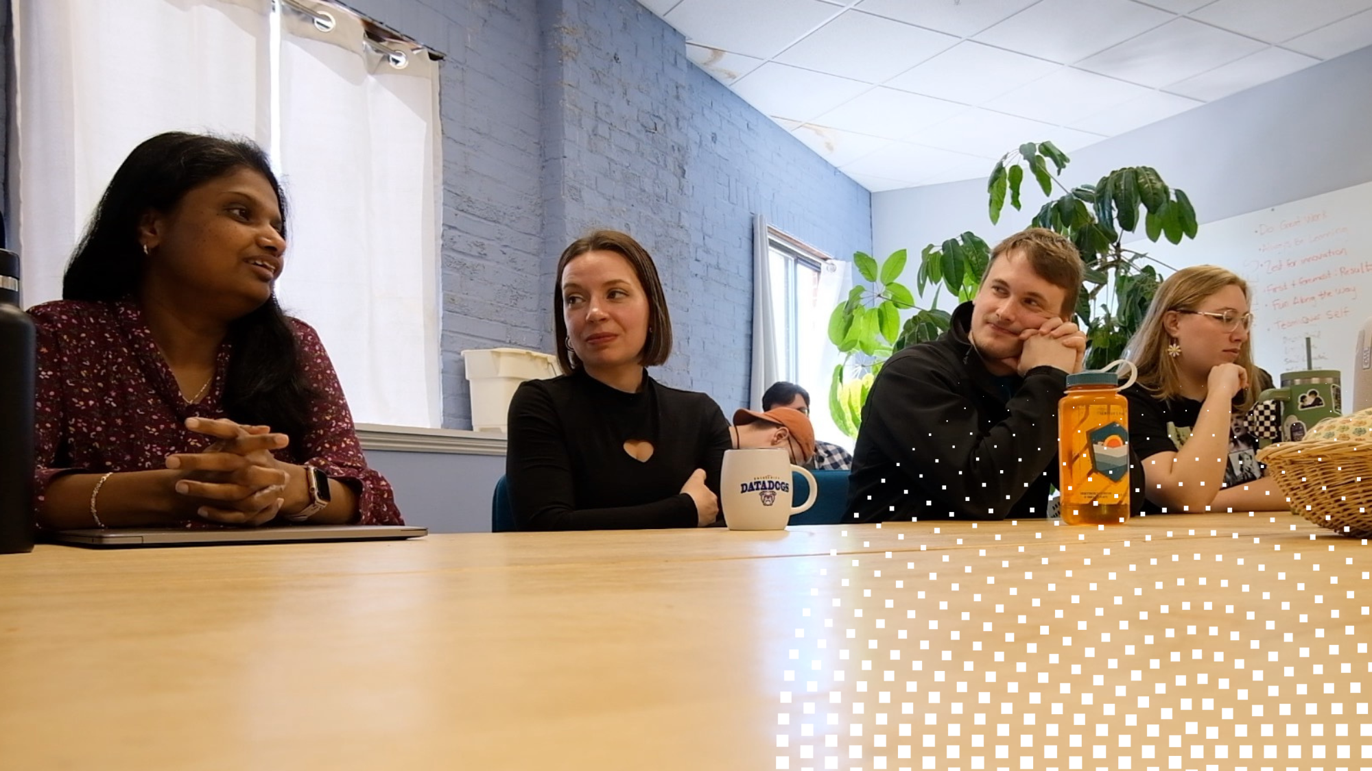 Members of the Energy Circle team sat around communal table discussing client strategy with small, white radius burst graphic overlay in bottom right hand corner