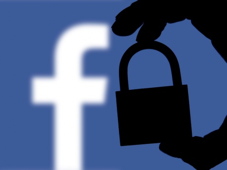 Facebook Logo with the Shadow of a Hand Holding a Lock